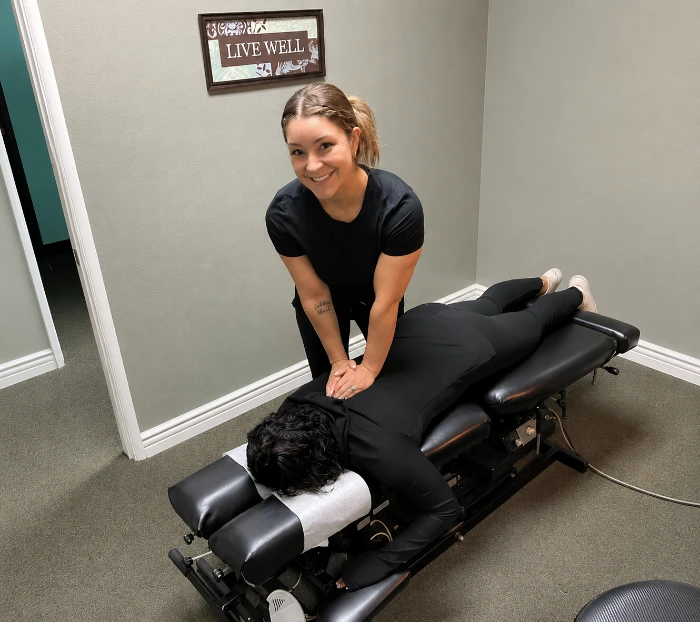 Chiropractor performing a back adjustment on a patient lying face down on a treatment table